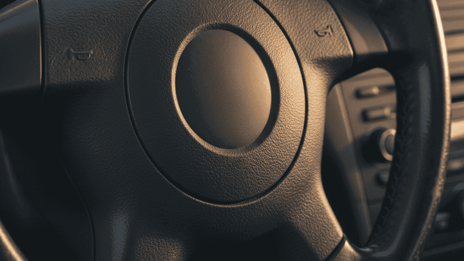 Volan automobila sa airbag poklopcem iz perioda 2008-2015, topla dnevna svjetlost pada sa strane kroz bočni prozor