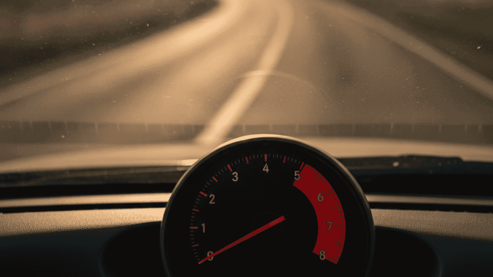 Temperature needle in the red zone on a car dashboard during a summer drive, with heat haze visible above the bonnet