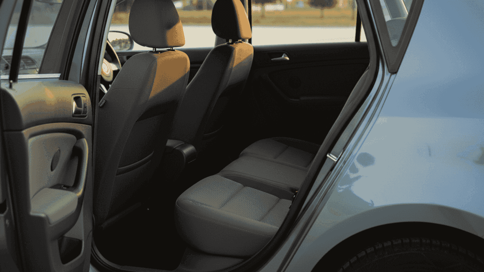 Detalj zadnjeg sjedišta polovnog evropskog kompaktnog auta sa vidljivim ISOFIX sidrištem između sjedala i naslona, kroz otvorena vrata vidi se i volan sa airbag-om